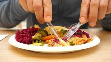 les mains masculines avec un couteau et une fourchette coupent un plat de poisson et de salade