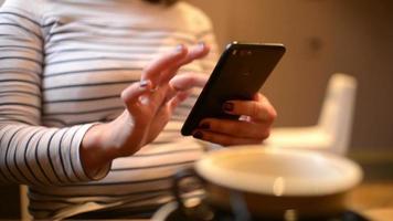 Femme brune d'âge moyen à l'aide d'un écran tactile de téléphone portable dans un café video
