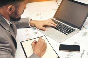 business man sitting writing text note and use computer on work table at office photo