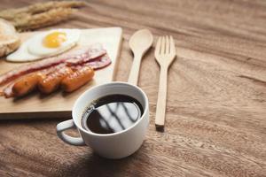 Desayuno con café negro y tortilla de tocino con salsa en la mesa de madera foto