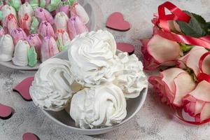 Handmade marshmallows on a light background in the form of roses, hydrangeas and tulips. There are flowers nearby. Women's day, Valentine's day. photo