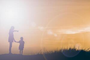 silueta madre e hijo al atardecer, apuntando al sol foto