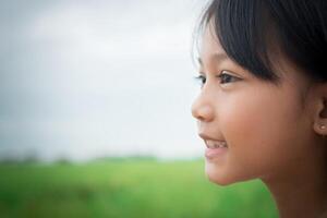 Close up of sweet little girl outdoors with smiling in the summer field. photo