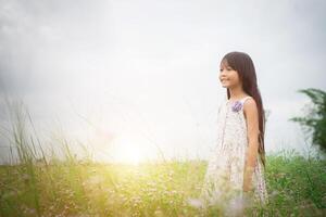 pequeña y linda niña asiática caminando entre el campo de flores moradas, concepto de disfrute de la libertad. foto