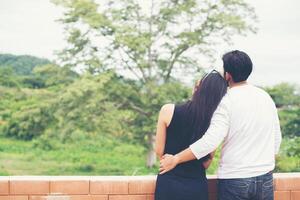 Young couple sitting hugging with their back to the camera,relaxing with natural. photo