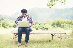 Young hipster man work on computer at the park in a sunny day. photo