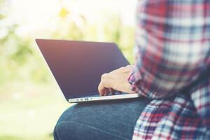 Young hipster man work on computer at the park in a sunny day. photo