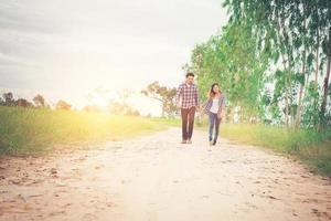 pareja joven hipster caminando por caminos rurales disfrutando de la naturaleza, pareja de amor, viajes de vacaciones, pasar tiempo juntos. foto