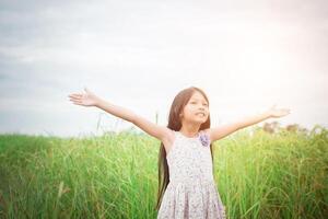 Little cute asian girl standing among the purple flower field sunshine day. Freedom enjoying with nature. photo