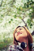 Young beautiful woman with headphones.listening to loud music outdoors on a green grass. photo