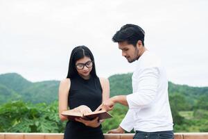 Young hipster couple enjoying a good read together while relaxing outdoors. photo