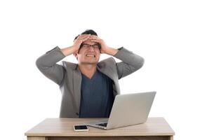 Stressed businessman work  with laptop sitting at table isolated on white background. photo