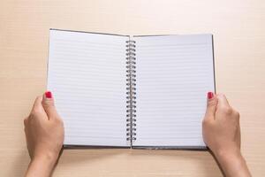 woman's hands holding a notebook, isolated on wooden background. photo