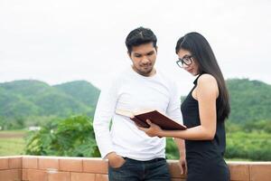 Young hipster couple enjoying a good read together while relaxing outdoors. photo