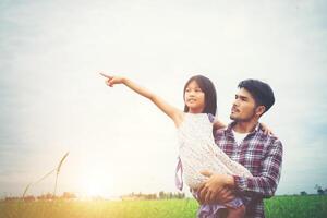 hija señalando y sonriendo con su padre en el campo de los prados. foto