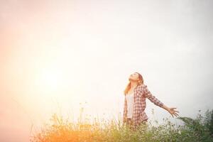 Young beautiful hipster woman in a flower field at sunset. Freedom enjoying with nature. photo