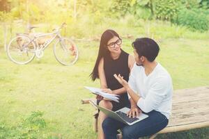 Young education couple sitting on the bench talk about study in the outdoors and good weather. photo
