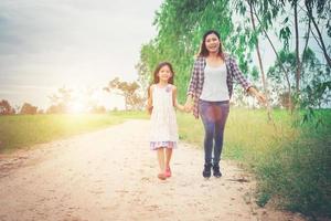 Mother and daughter are having fun walking from down rural road. photo