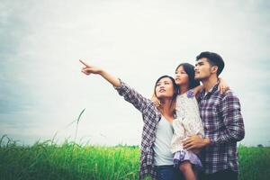 Family of mother, father and child on meadow, dad carrying the daughter. photo