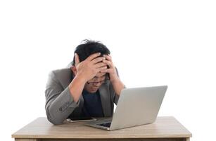 Stressed businessman work  with laptop sitting at table isolated on white background. photo