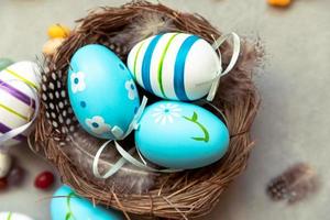 Happy Easter concept. Preparation for holiday. Colorful decorated blue easter eggs in nest on concrete stone grey background. Simple minimalism flat lay top view. Postcard background banner on Easter. photo