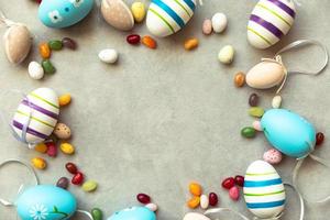 Happy Easter concept. Preparation for holiday. Easter eggs candy chocolate eggs and jellybean sweets on concrete stone grey background. Flat lay top view copy space banner. photo