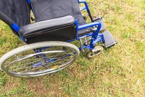 Empty wheelchair standing in hospital park waiting for patient services. Wheel chair for person with disability parked outdoor. Accessible for person with disability. Health care medical concept. photo