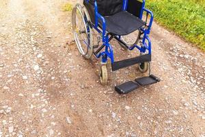 Empty wheelchair standing on road waiting for patient services. Wheel chair for people person with disability parked outdoor. Accessible for person with disability. Health care medical concept. photo