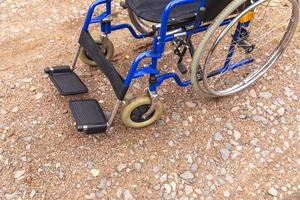 Empty wheelchair standing on road waiting for patient services. Wheel chair for people person with disability parked outdoor. Accessible for person with disability. Health care medical concept. photo