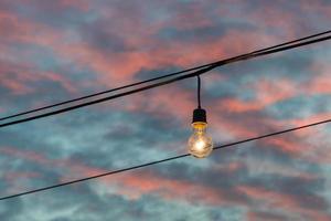 Light bulb glowing on sunset background photo