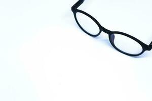 Black Eyeglasses in The Corner of Minimalist White Background with Oblique Top Shot, Landscape Mode photo