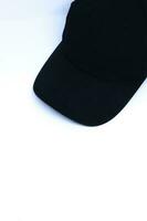Oblique Top Shot of A Black Hat in The Corner of Minimalist White Background, Portrait Mode photo