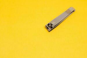 A Grey Nail Clipper in The Corner of Yellow Backrgound photo