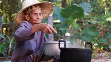 una anciana encendiendo un fuego para cocinar video