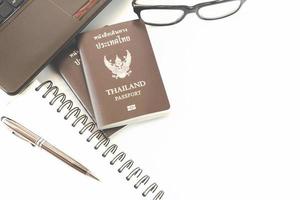 Travel accessories costumes. Passports Thailand, Preparation for travel, Notebook pen on top, glasses, and laptop or computer for vacation time, soft focus. photo