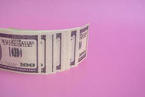 One hundred dollar bills on a pink background, closeup with copy space photo
