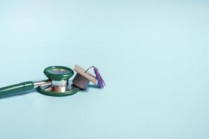 Graduation cap with stethoscope and numbers 2022 on blue background, closeup with copy space. Medical education concept. photo