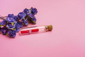 A bouquet of blue roses and a bottle with a message on a pink background. Banner for valentine's day or mother's day copy space. photo