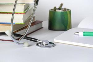 mesa de médico o estudiante con estetoscopio, bloc de notas, libros. educación médica o concepto de formación avanzada. copie el espacio foto