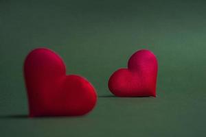 Composition for Valentine's Day. On a green background, red hearts closeup with copy space photo