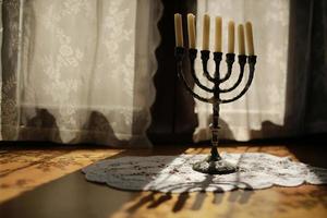 Candles in vintage copper candle holder on wooden table near the window in country house interior photo