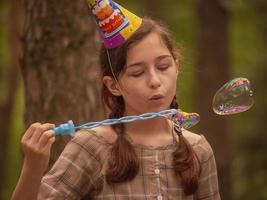 Teenage girl 11 years old. Birthday holiday. Soap bubble blowing. photo