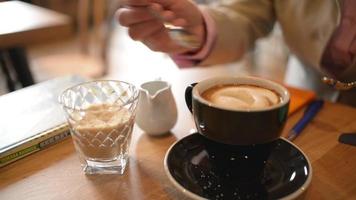 Frau setzt und rührt den braunen Zucker in eine Tasse Kaffee - Nahaufnahme Tageslicht video