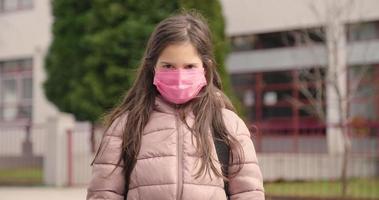 eine Zeitlupenaufnahme eines kleinen Mädchens mit einer Schutzmaske, das zur Schule geht video