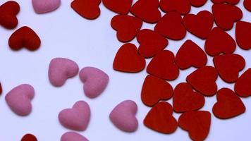 A lot of small multi-colored hearts rotates on a white background. video