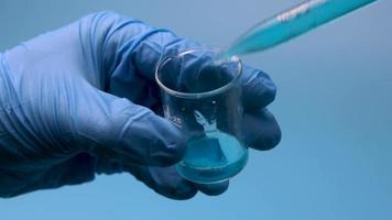 Taking a blue liquid is taken with a pipette from a small flask. video