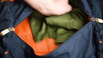 un uomo raccoglie i vestiti in una borsa sportiva, primo piano. video