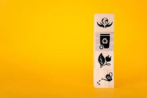 Ecology concept with icons on wooden cubes, yellow background. photo