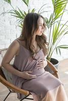 Pregnant girl sitting in a chair on a white background. photo