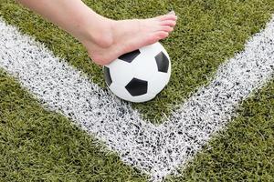 girl foot on the soccer ball on green field photo